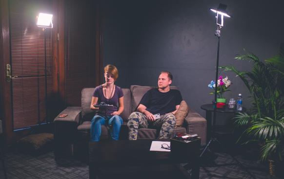 Man & Woman sitting on couch with production equipment