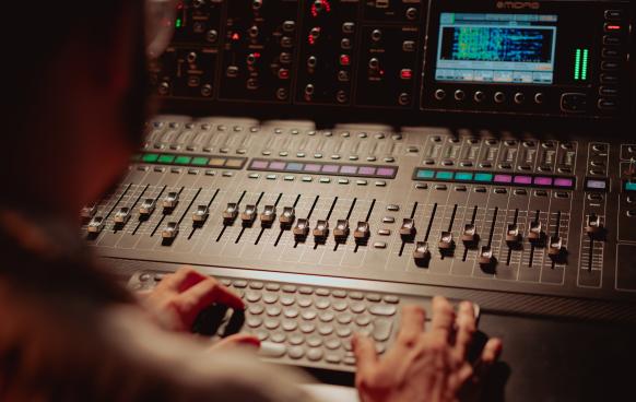 Photo of a person at an audio mixing board in a studio