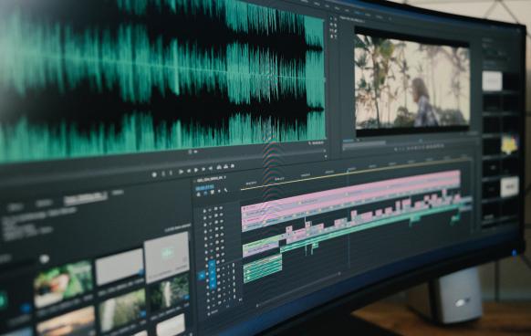 Photo of a wide curved screen with Adobe Premiere Pro open to a video editing project