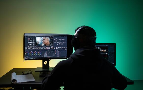 Photo of a man with headphones on color correcting video in DaVinci Resolve