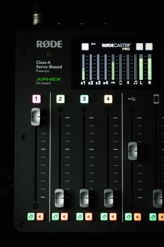 Photo of a Rodecaster Pro showing faders and the display screen for inputs