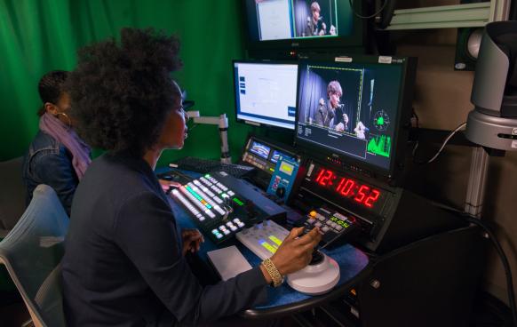 Woman in control room looking at screen to adjust camera position