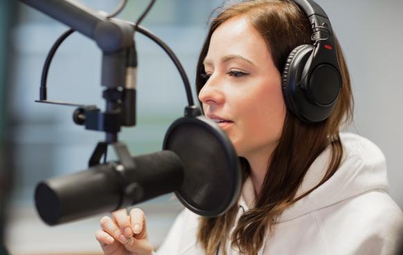 Woman wearing headphones talking into microphone