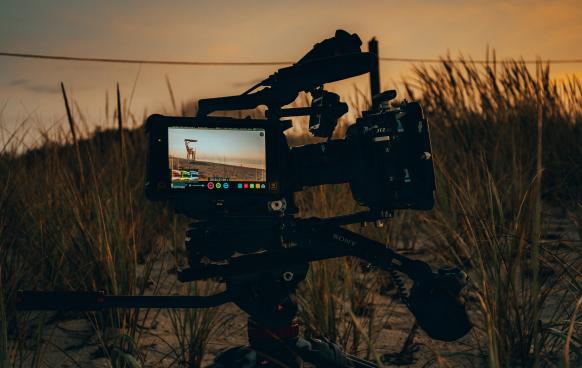 Cinema camera in a field at sunset (Photo by Billy Freeman on Unsplash)