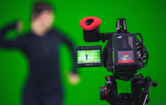Photo of a camera pointed at a person in from of a green screen Photo by Ryan Garry on Unsplash