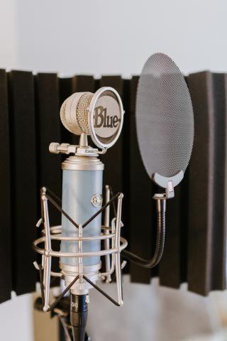 A photo of a Blue brand microphone with a pop filter setup to minimize plosives.